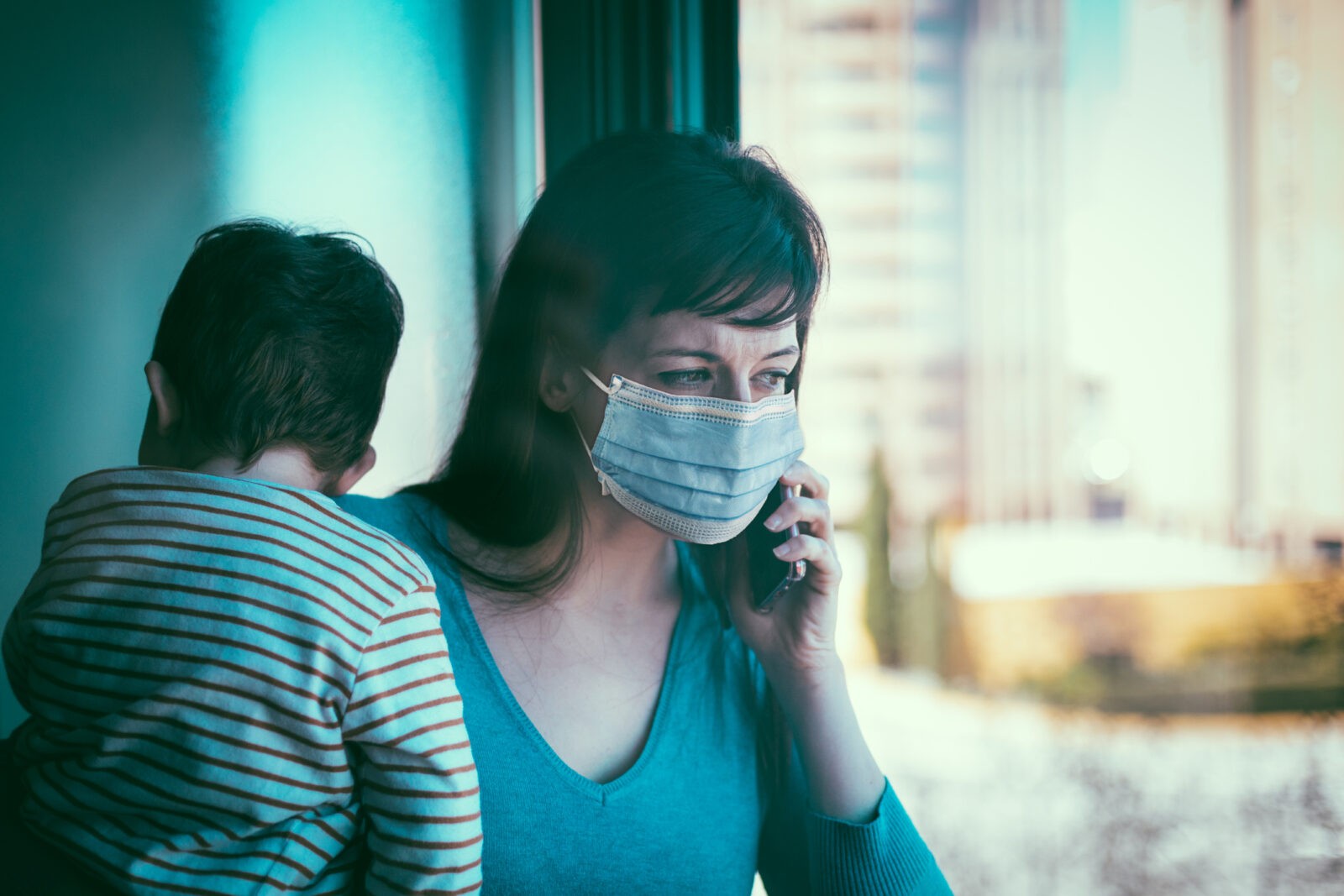 Worried mother holding her child, making a phone call.