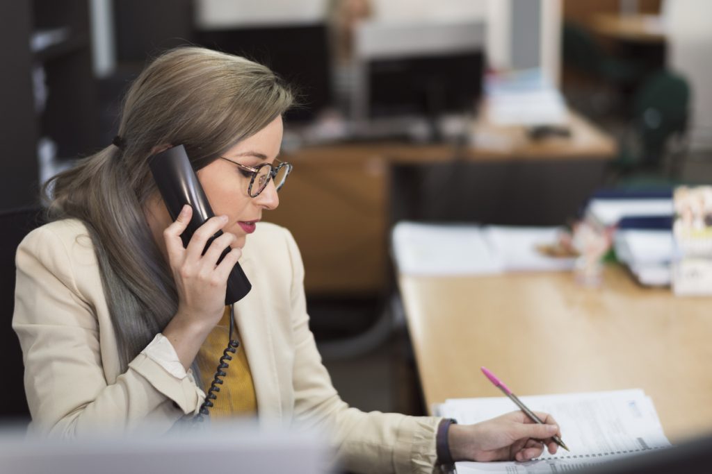 Businesswoman taking notes and talking on the phone