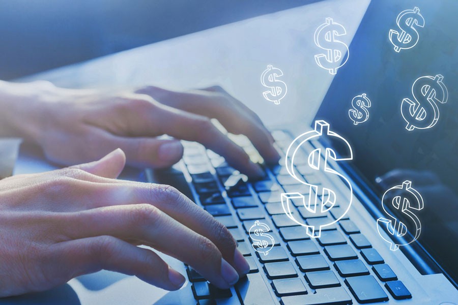 Someone typing on a laptop with dollar signs in the air
