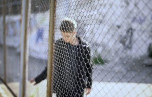 Teen boy behind fence confinement, boarding school restrictions, broken future