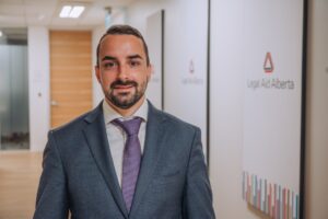 Picture of LAA lawyer Bjoern Wolkmann in front of a Legal Aid Alberta sign.