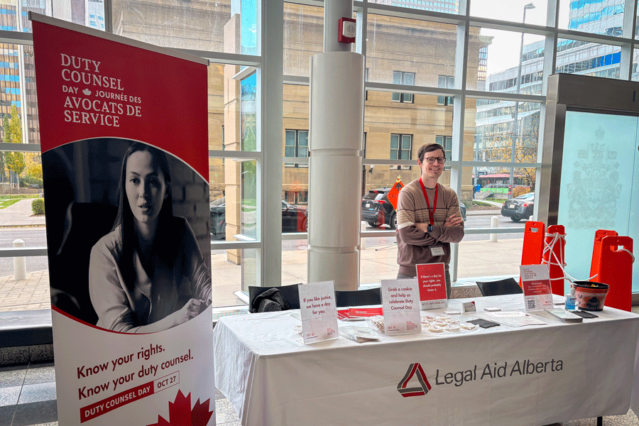 Legal Aid Alberta staffer standing at a table informing about Duty Counsel Day