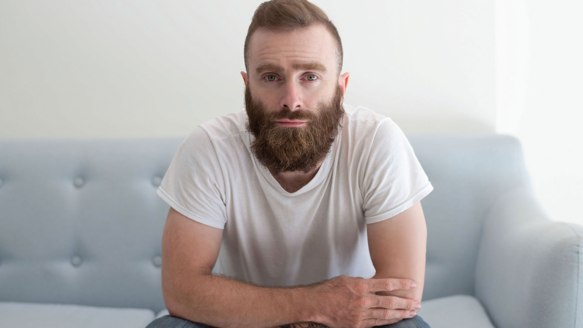 A man with a bear sits on a couch