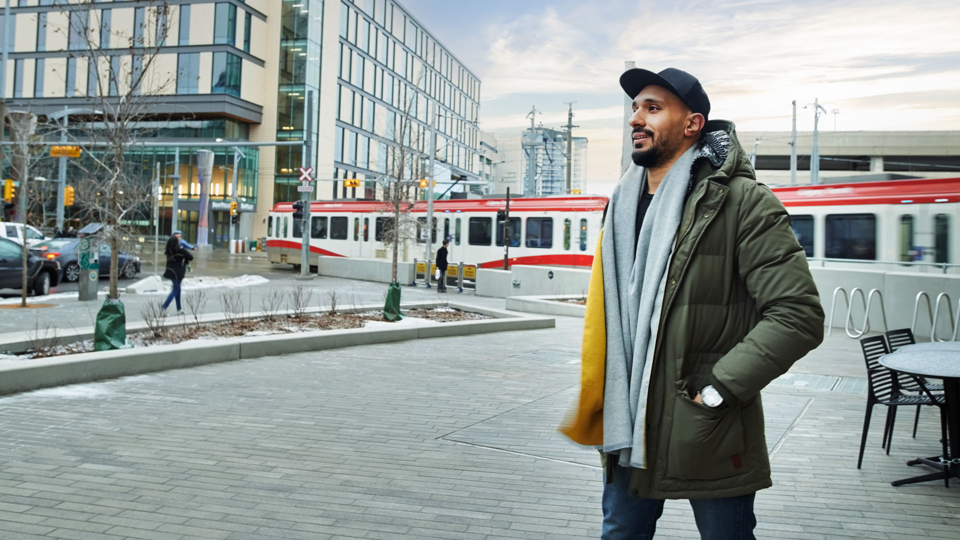 A man walks in downtown Calgary with the C-Train in the background.