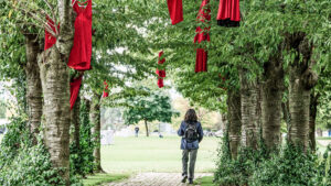 A red dress art installation hangs in trees
